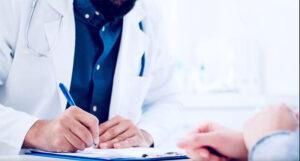 View of doctor's and patient's hands. Doctor is writing.